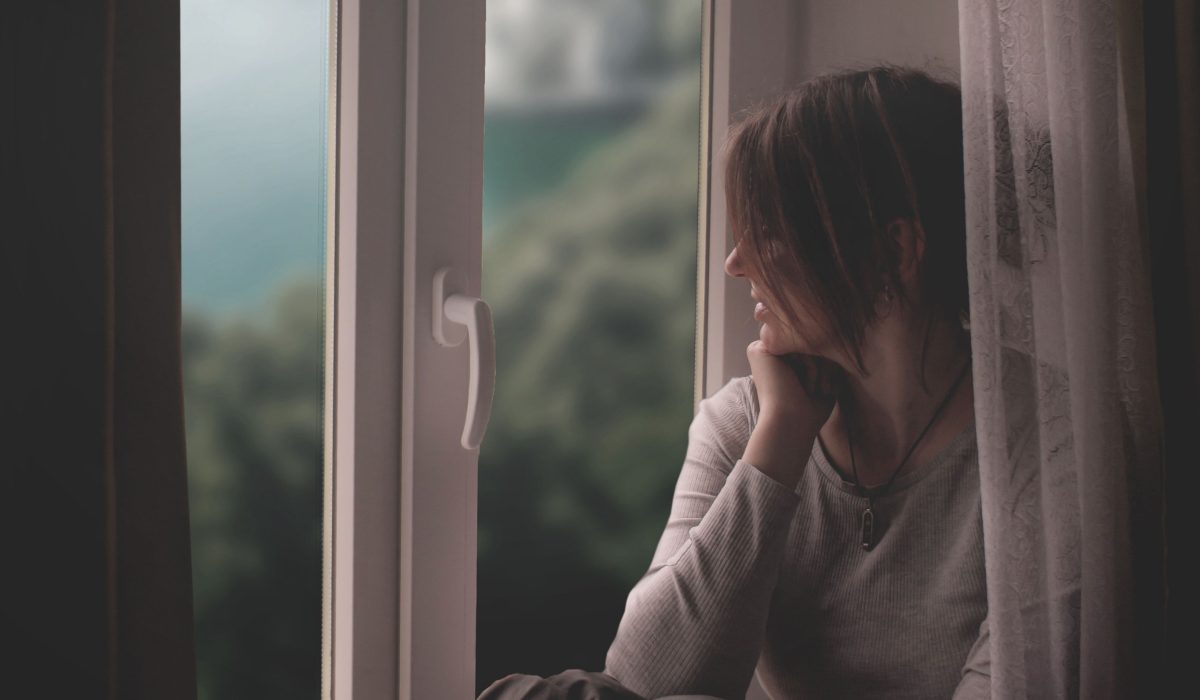 Personne assise près d'une fenêtre dans un moment de réflexion